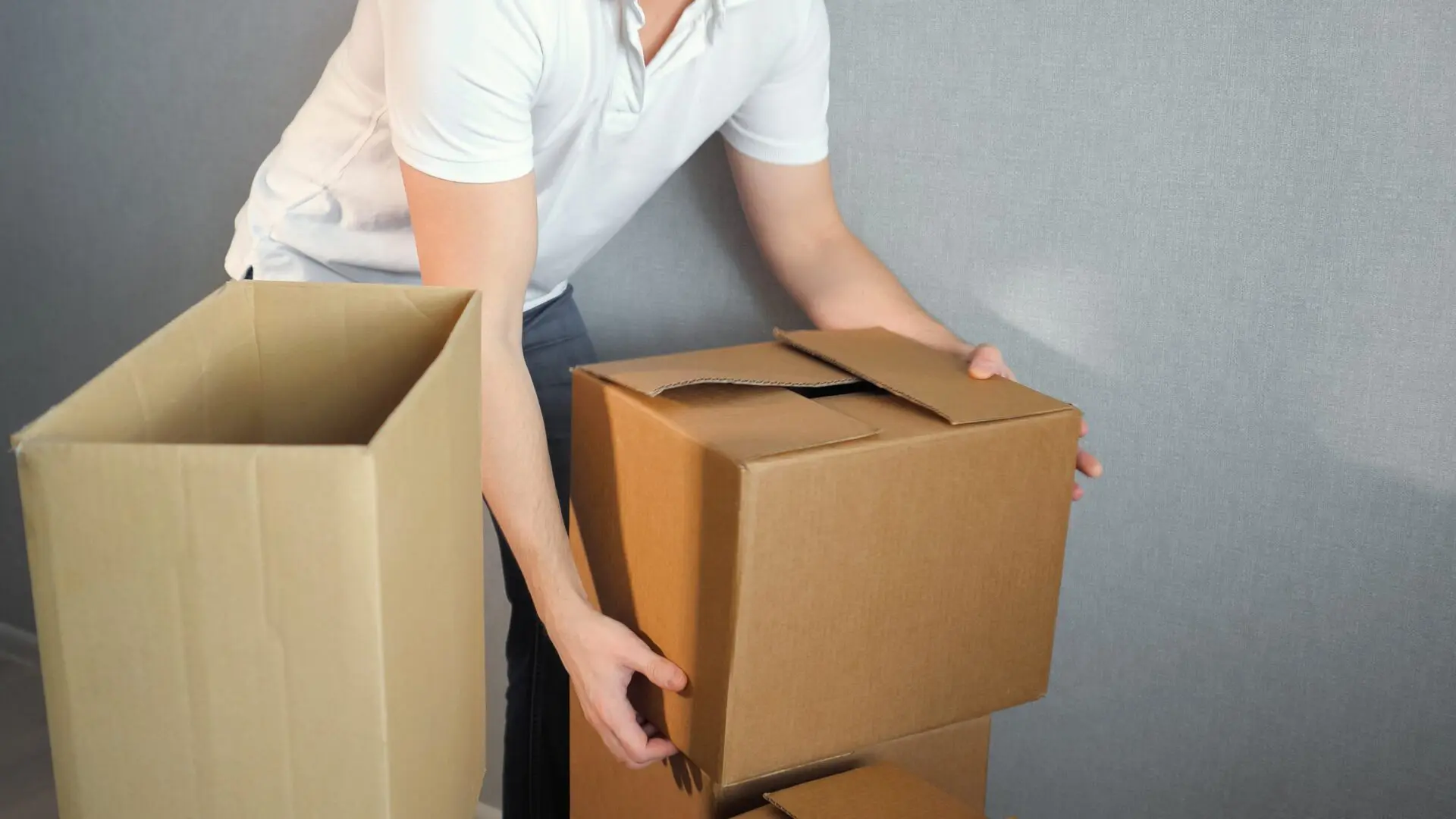 Mover stacking cardboard boxes indoors carefully.