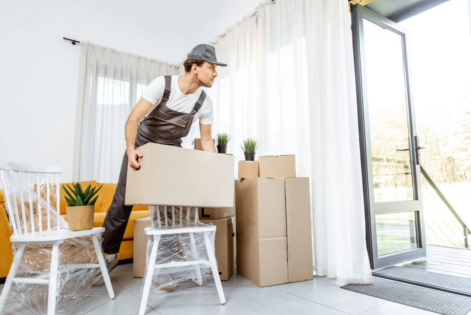 Mover carrying a box in a bright room.