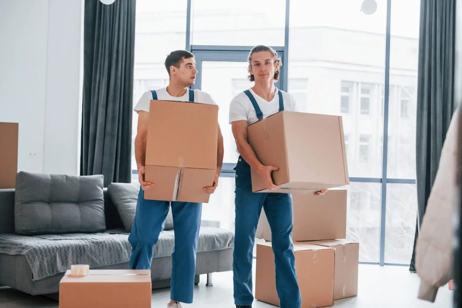 Two movers lifting boxes in a room
