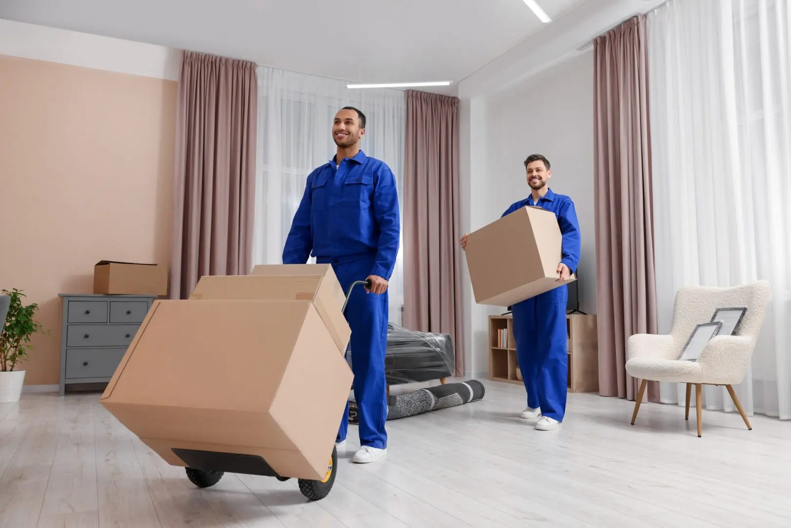 Movers transporting boxes in a bright room.