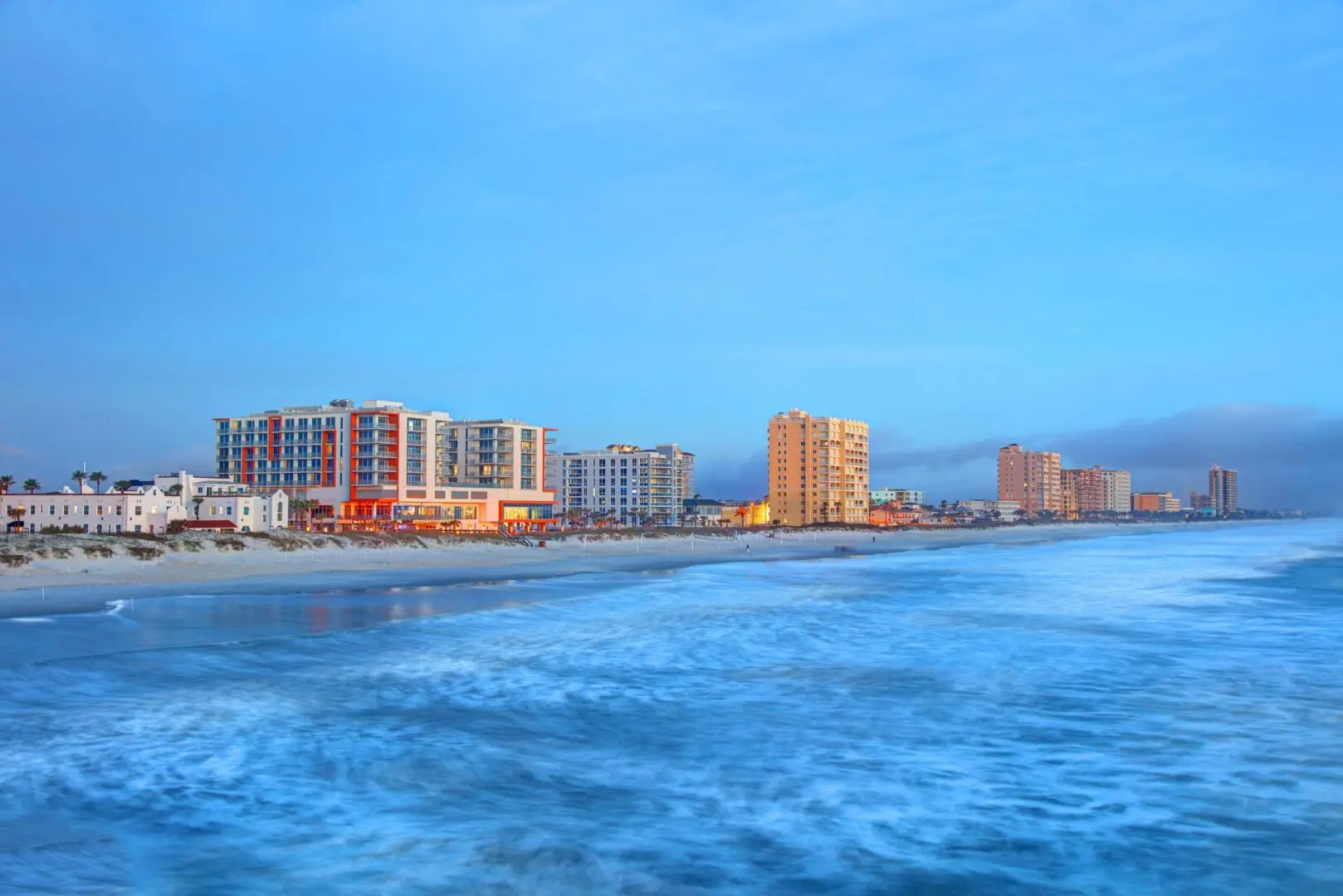 Coastal skyline with buildings and ocean waves.