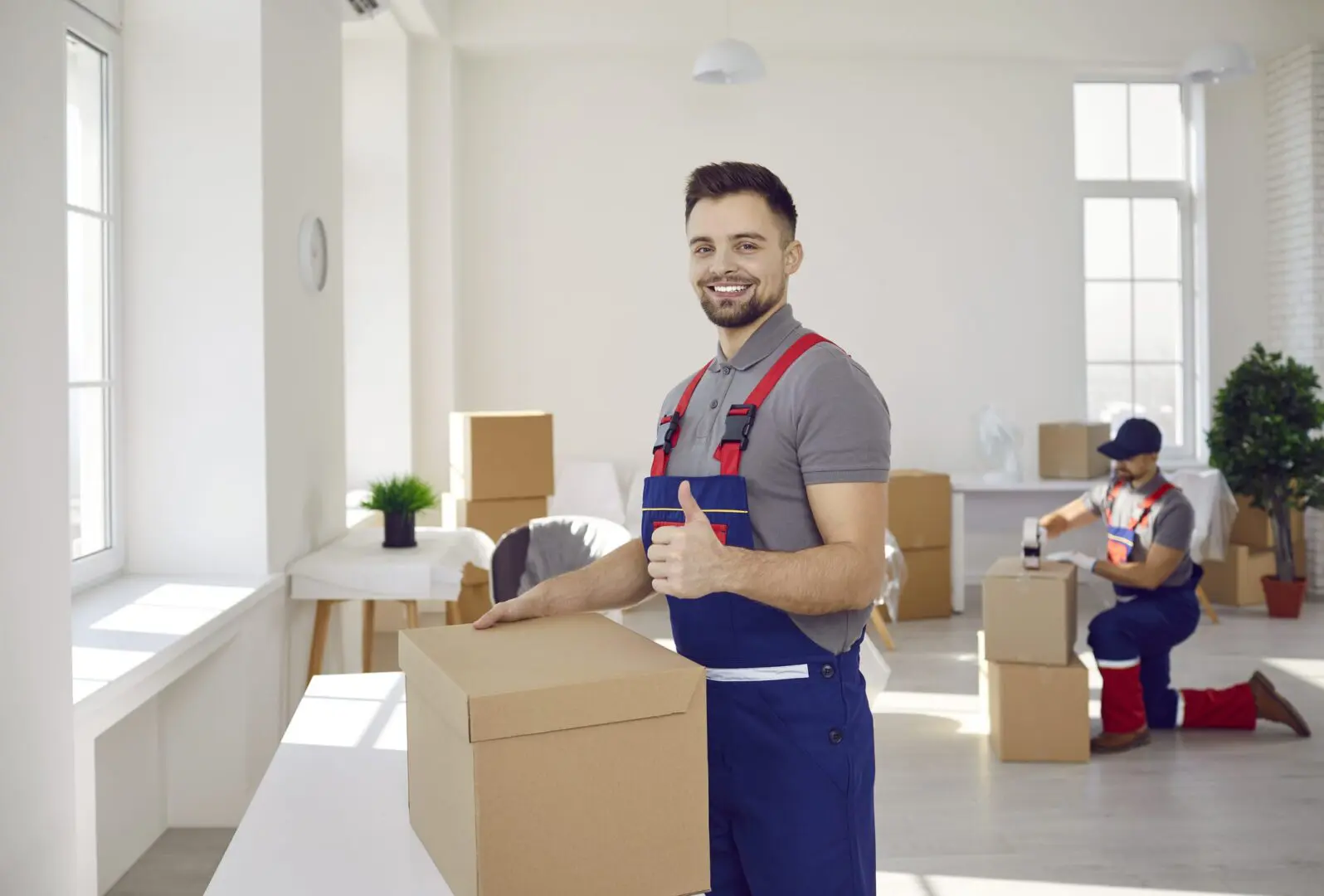 Smiling mover with boxes in a bright room.