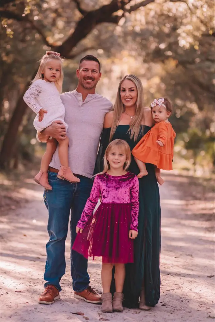Family posing together in a wooded area.